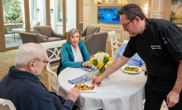Our chef serving meals to seniors in a dining area.