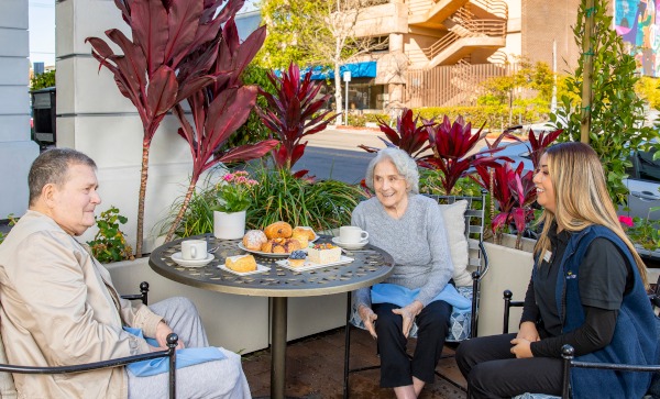 A senior woman enjoying a spread of cakes and pastries.